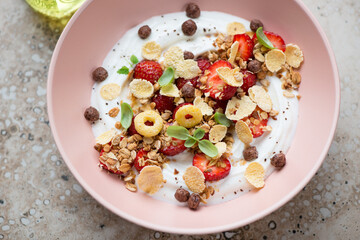 Roseate bowl with greek yogurt, strawberries, flakes and granola, horizontal shot, middle close-up