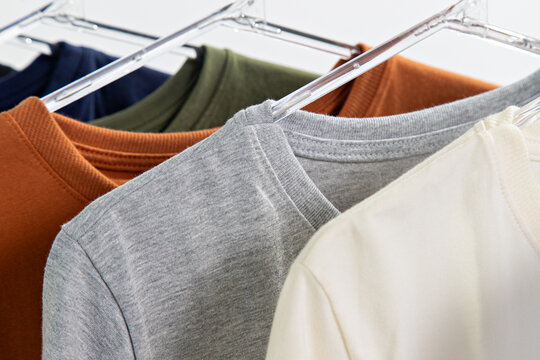 Camisetas b&aacute;sicas sobrepostas em cabides de roupas