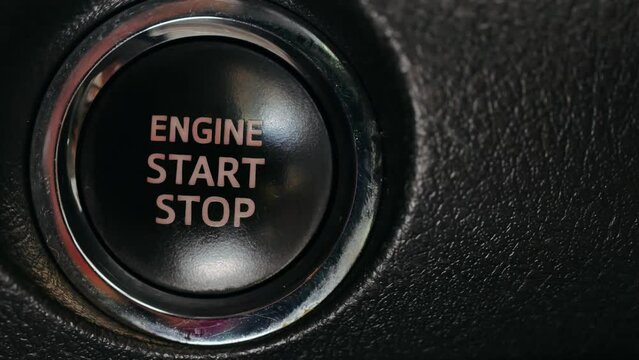 Close-up of finger press  pushing start stop button in car. macro hand starting car with button. Male driver using start button in modern car