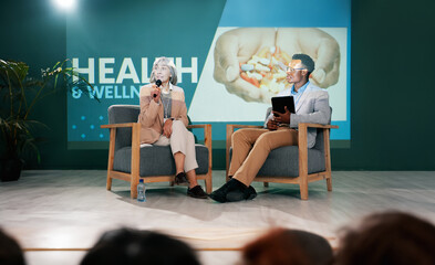 Speaker, health seminar and speech of woman on stage with host on mic and tablet at event....