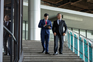 Asian multi generation business men wear suit working together. Senior and young businessman discussing agreements while walking to meetings with partners and connections. Discuss business strategy.