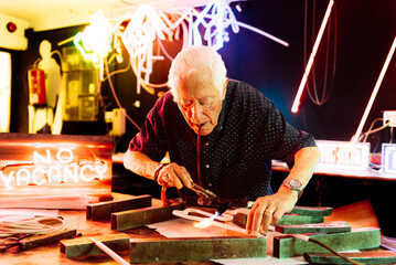 Senior Man Working on a Neon Sign in His Workshop - Powered by Adobe