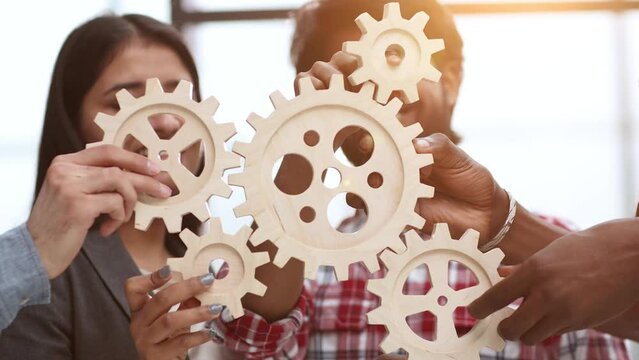 Office worker holding cog wheel as unity and teamwork in corporate workplace concept.