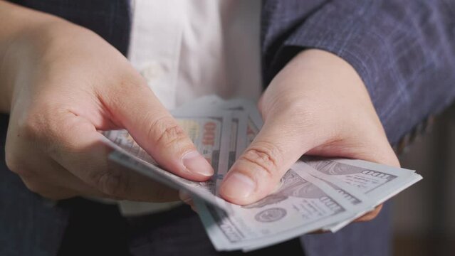 Close up hand holding and counting the currency symbolizes financial success and wealth management, making relevant for savings, income, cash flow, economic stability and profit of businessman. 