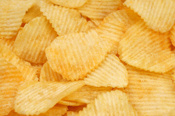 Crispy potato chips in macro. Golden fried potatoes close up. Potato snack for unhealthy fast food.	
