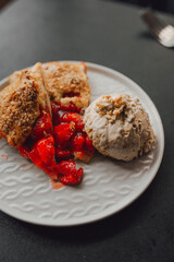 pie with strawberries and ice cream on a plate, dark background