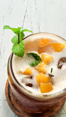 Mango iced tea with mint leaves which tastes very refreshing. Iced tea on a white table is very fresh to enjoy in the hot summer