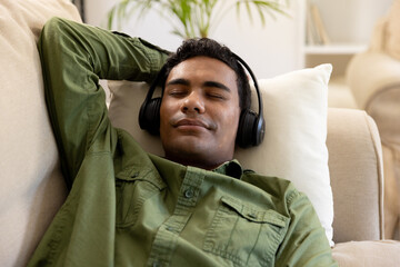 Obraz premium Young biracial man relaxes at home with headphones