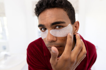 Young biracial man applies skincare products at home