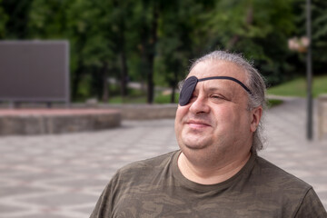 Portrait of a blind, visually impaired man with a black medical bandage on his eye smiling