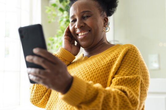 Happy senior african american woman using smartphone at home