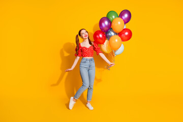 Full length photo of lovely young lady hold air balloons look empty space dressed stylish red garment isolated on yellow color background