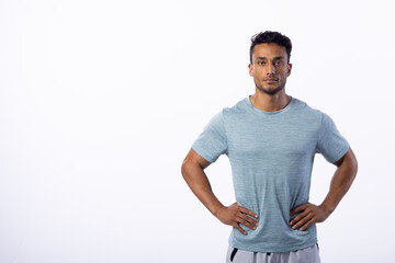 Confident young biracial man stands with hands on hips, with copy space on white background