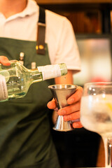 Hands of a bartender measuring the dose of alcohol before preparing the drink. Vertical