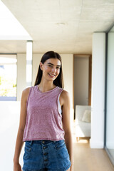 Teenage Caucasian girl stands smiling in a bright home setting