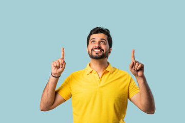 Fototapeta premium Happy Indian Asian Bearded Man Pointing at Copy Space, Looking Shocked, Blue Background