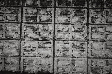 A wall made of bricks with a lot of cracks and holes. The wall is very old and has a lot of wear and tear