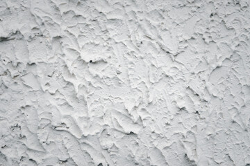 The wall is covered in white paint and has a rough texture. The wall appears to be unfinished and has a somewhat unfinished look to it