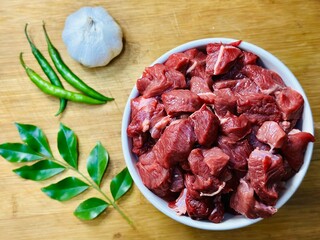 Sliced beef in a bowl on blurred wooden background 