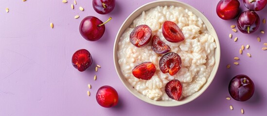 Top view of rice pudding with roasted plums on a purple background, providing a clear copy space image.