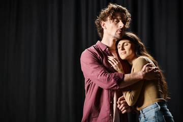Handsome man and beautiful woman sharing a tender hug in a theater rehearsal.