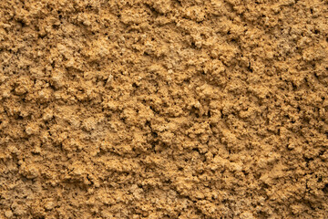 A wall with a brown and tan texture. The wall is made of concrete and has a rough surface