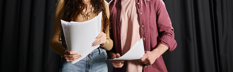 A good-looking man and woman stand side by side during theater rehearsals.