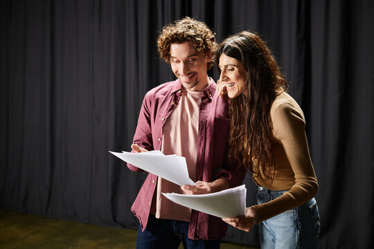 A man and woman study a script together, deeply engaged.