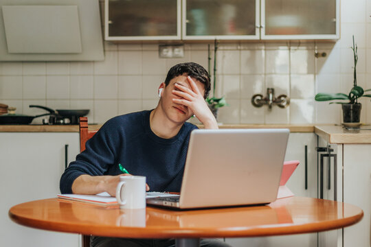 Frustrated young man working from home on a laptop