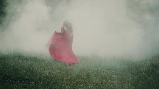 fantasy woman runs in thick fog gothic dark forest, red dress long train waving,fabric flies in slow motion. Scared mistery girl princess red hair, medieval romantic lady noblewoman, back rear view