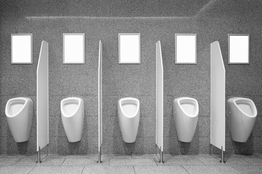 Blank advertising posters on the wall by the urinals in toilet