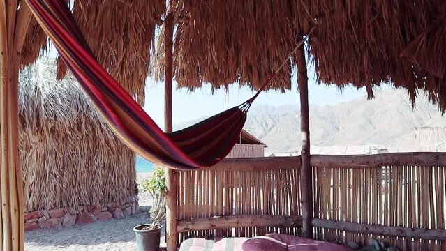 Hammock hanging at the entrance of the hut by the sea