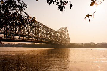 The Hooghly river and the iconic Howrah bridge in Calcutta are seen in the morning at sunrise....