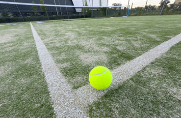 Tennis or paddle balls on synthetic grass of paddle court with net on the background