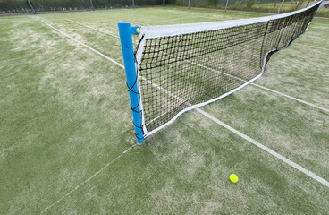 Tennis or paddle balls on synthetic grass of paddle court with net on the background