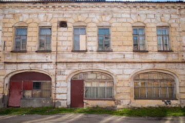 the facade of an old two-storey leaning brick building with large windows on the ground floor