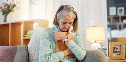 Senior woman, picture and sad with grief for mourning, memory and remember past life in nursing home. Elderly widow, hug and photo frame for depression with mental health, nostalgia and retirement