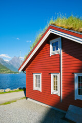 Traditional Scandinavian houses with moss on the roof. Beautiful mountain lake in Norway. Nature in the fjords. Vacation and travel in summer Norway.