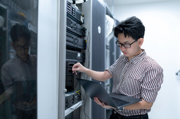 Computer engineer is setting up network in server room,Systems Maintenance Technician,Male engineer working in server room at modern data center