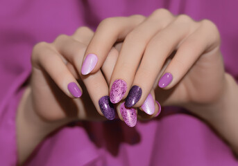 Fototapeta premium Female hands with pink nail design. Glitter nail polish manicure. Woman hands on pink fabric background