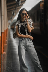 Stylish young woman striking a pose on a train platform while awaiting her journey to begin