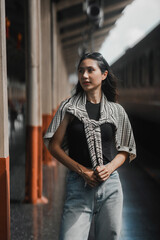 Young woman in casual clothes waits alone at a train platform, lost in thought, ready for a new adventure