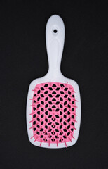 Red and pink massage comb on a black background. A hair and body brush.