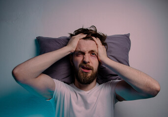 Top view man having trouble sleeping  head on a pillow hands on the head 