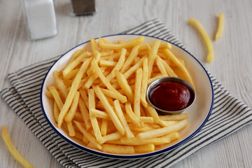 Homemade American French Fries with Ketchup on a Plate, side view.