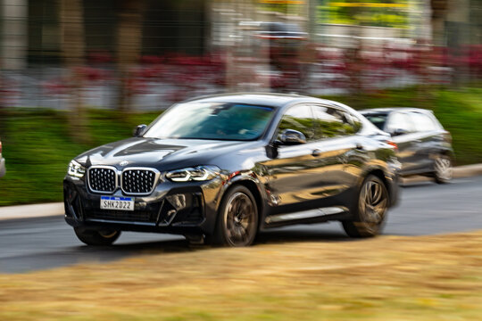 Black BMW X4 cruising city street, Luxury SUV in movement, High Resolution Panning Shot