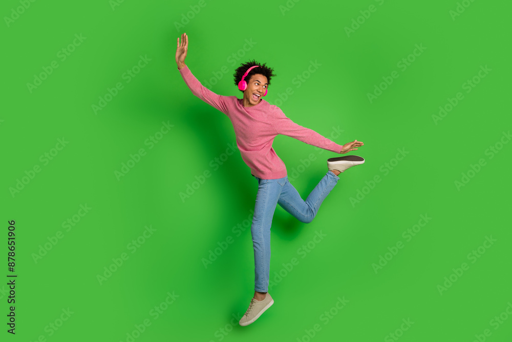 Poster full length photo of handsome good mood guy wear pink sweater headphones jumping high emtpy space is