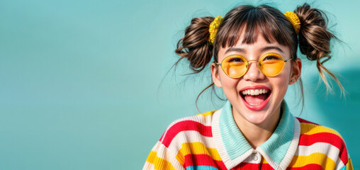 Young Asian woman in glasses laughs with open mouth, light blue background, copy space for text