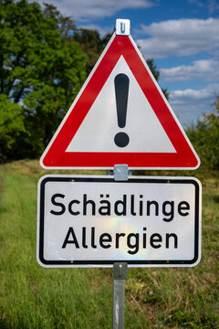 street sign in natural background with warning text "Schaedlinge,Allergien" in Brandenburg (Germany)