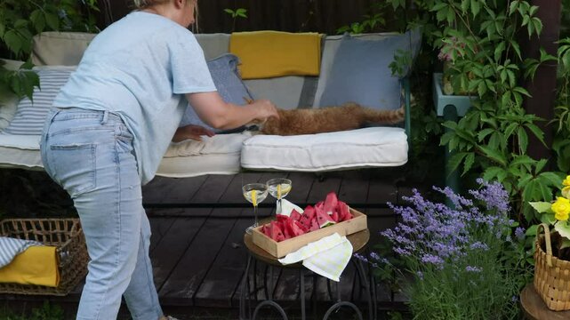cozy place in the summer garden, garden swing with soft cushions curled with grapes and decorated with flowers in cachepots